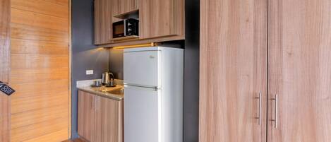 A compact kitchen with wooden cabinets, a built-in microwave, and a white refrigerator.