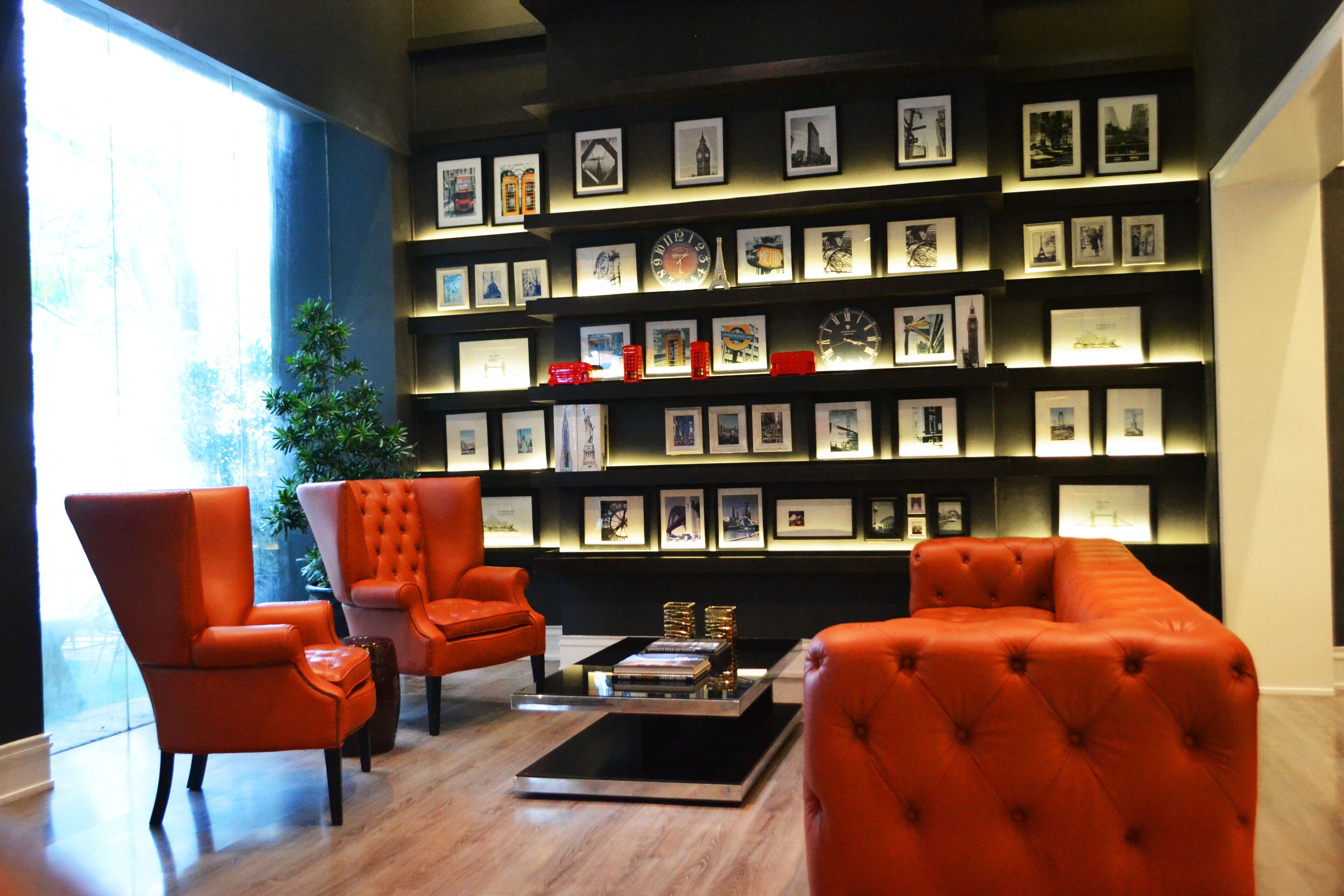 A modern living room with orange furniture, a coffee table, and a wall of framed pictures.