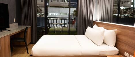 Ein modernes Hotelzimmer mit einem hölzernen Bett, einem Schreibtisch und einem großen Fenster mit Vorhängen.