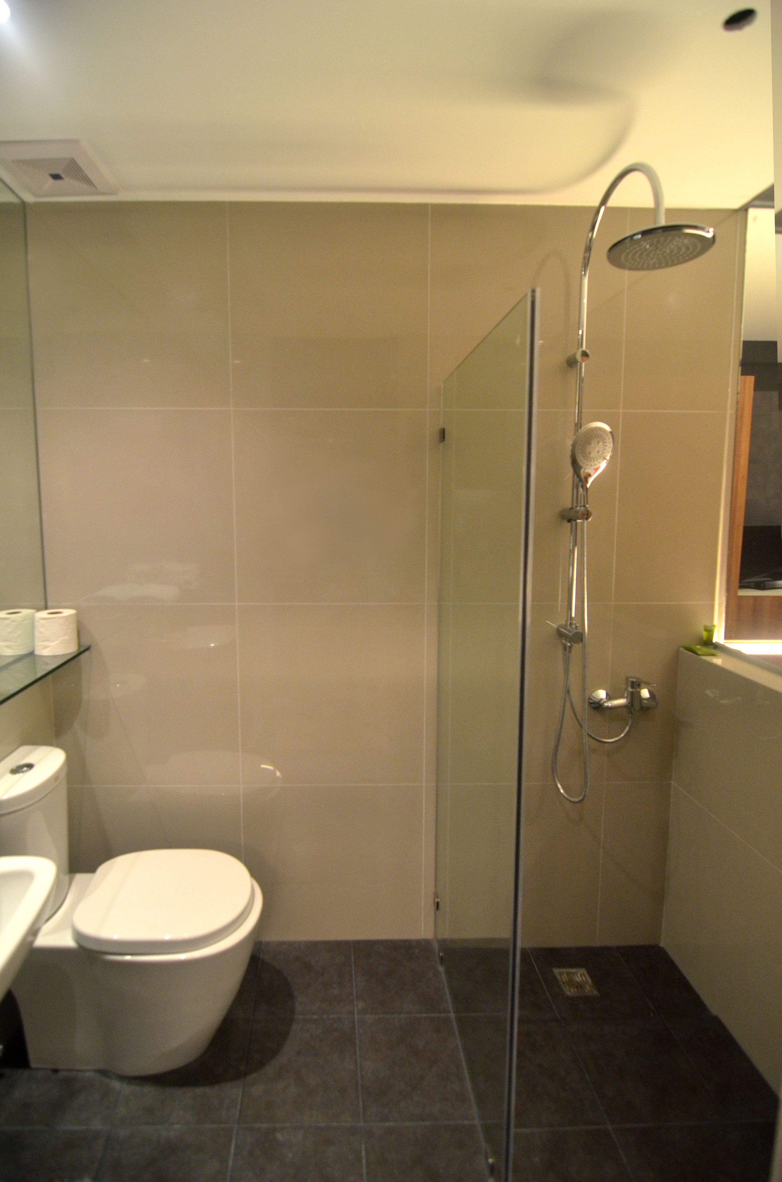 Een badkamer met douche, toilet en wastafel.