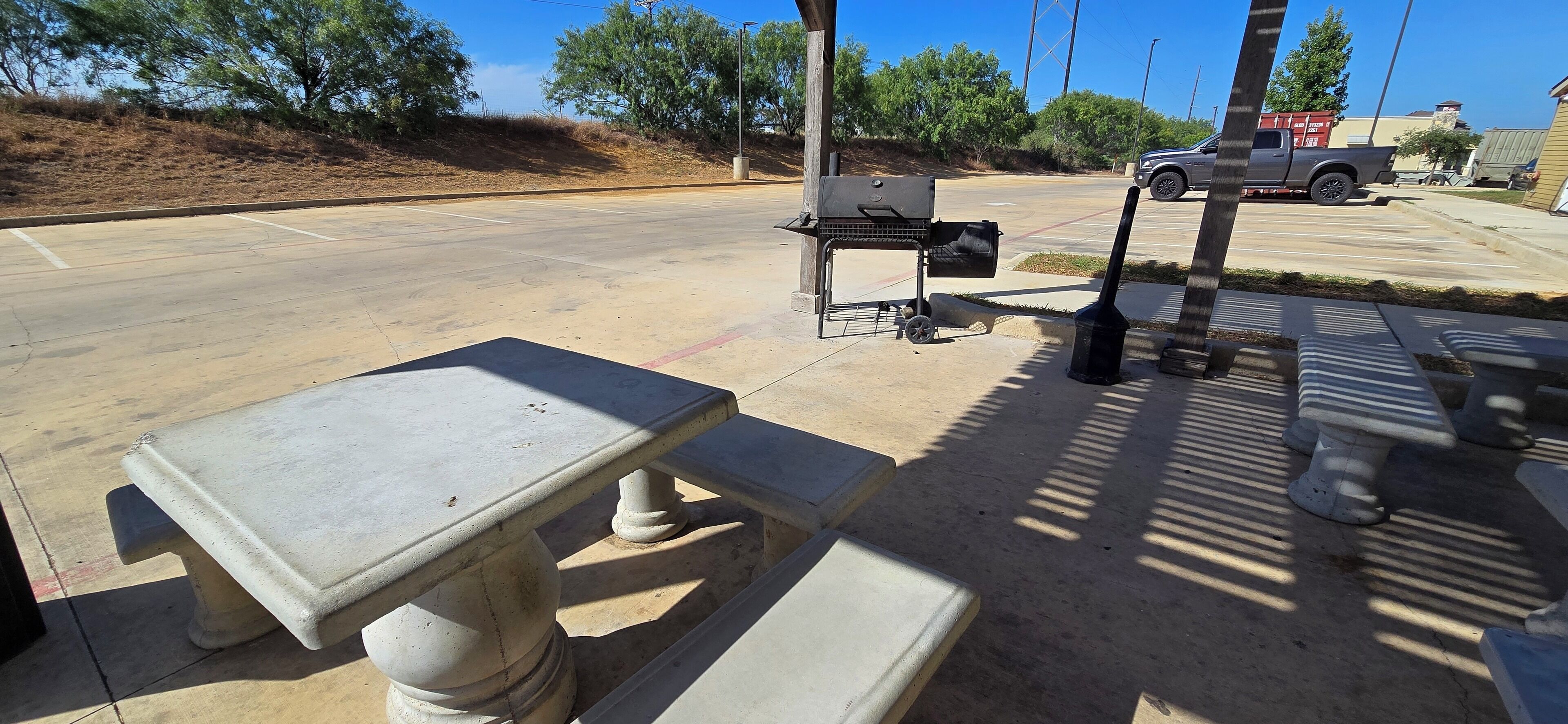 A parking lot with a barbecue grill and a table.