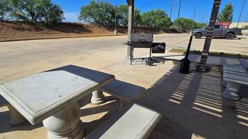 A parking lot with a barbecue grill and a table.