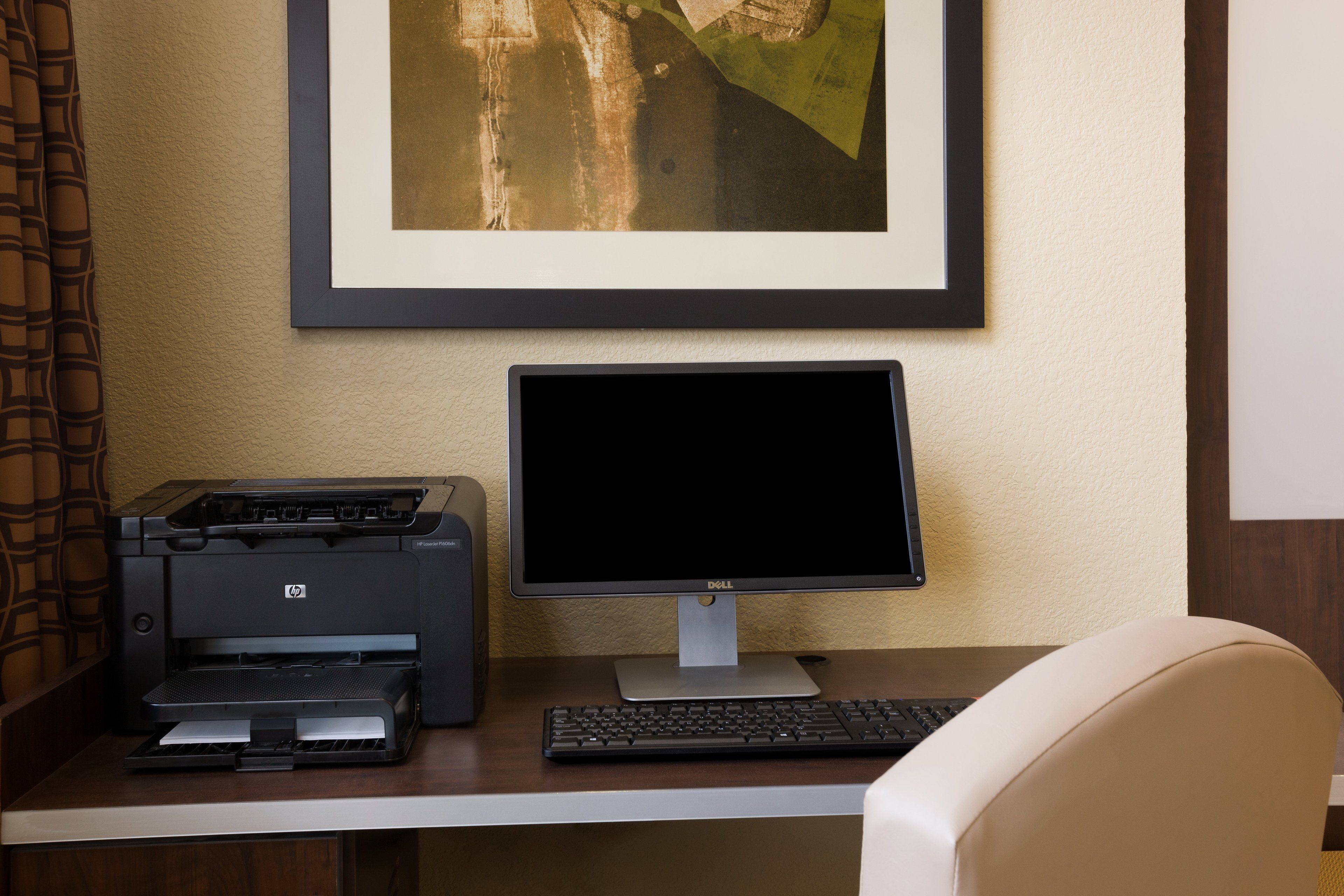 A desk with a printer, a monitor, and a keyboard.