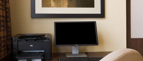 A desk with a printer, a monitor, and a keyboard.