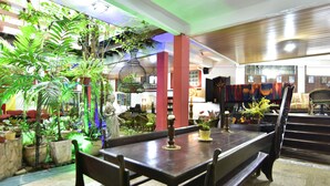 A dining area with a long table, chairs, and potted plants. - Estalagem do Porto (Arraial do Cabo)