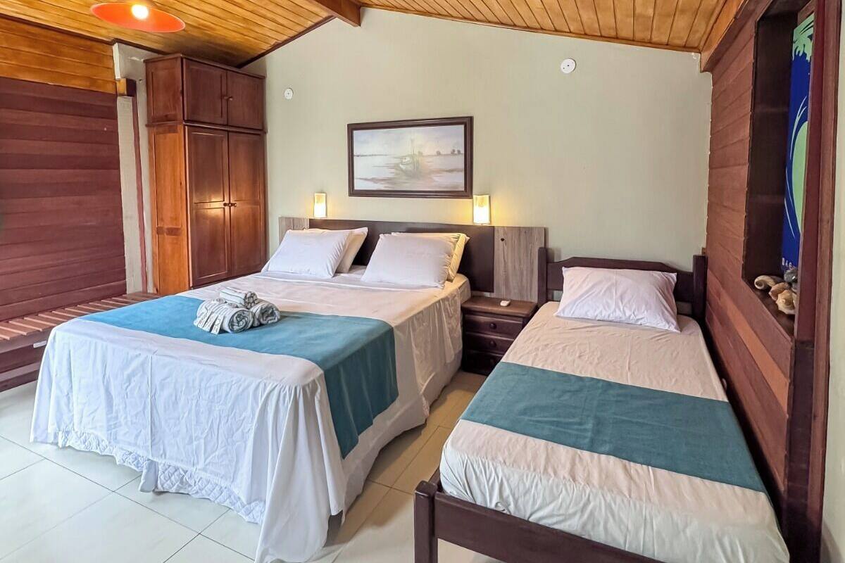 A room with two beds, wooden ceiling, and a framed picture on the wall.