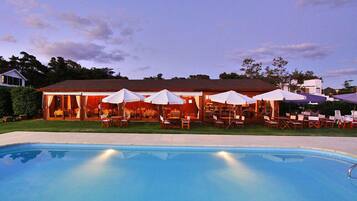 Una piscina al aire libre, sombrillas, sillones reclinables de piscina