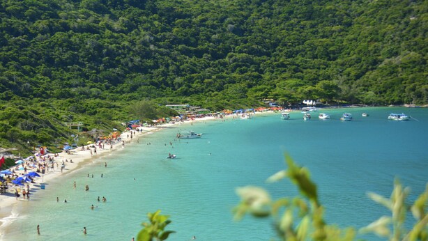 A beach with clear turquoise water, surrounded by lush green hills. - Hotel da Canoa (Arraial do Cabo)