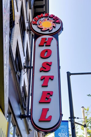 Neonbord voor een hostel met een zon- en dakraamontwerp, bevestigd aan een gebouw.