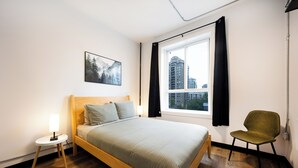 Une chambre moderne avec un lit en bois, une petite table de chevet, une chaise, une fenêtre avec des rideaux et une vue sur la ville.