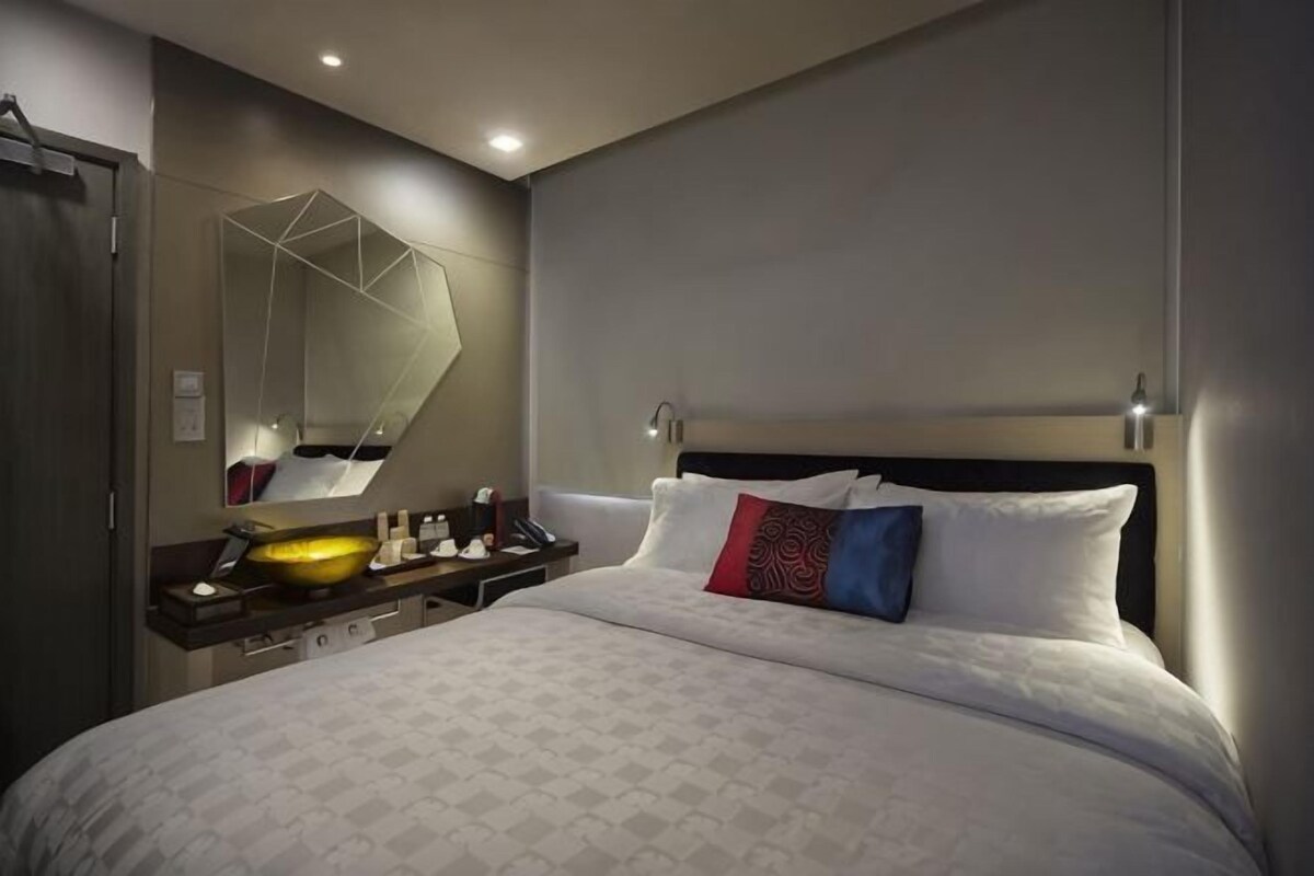 Ein Hotelzimmer mit einem großen Bett, einem Nachttisch mit Spiegel und einer Wandleuchte.