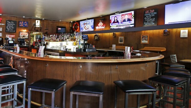 A bar area with a curved counter, multiple stools, and televisions displaying news. - Town House Motel – Historic Old Town Eureka (Eureka)