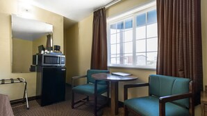 A hotel room with a bed, a desk with a computer, a microwave, a chair, and a window with curtains. - Town House Motel – Historic Old Town Eureka (Eureka)