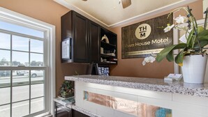 A reception area with a counter, a sign for Town House Motel, a window with a view of the street, and a potted orchid. - Town House Motel – Historic Old Town Eureka (Eureka)