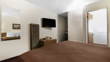 Habitación de hotel con una cama grande, un televisor de pantalla plana en la pared, un aparador y una puerta.