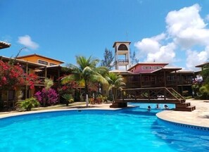 Una piscina al aire libre, sombrillas, sillones reclinables de piscina