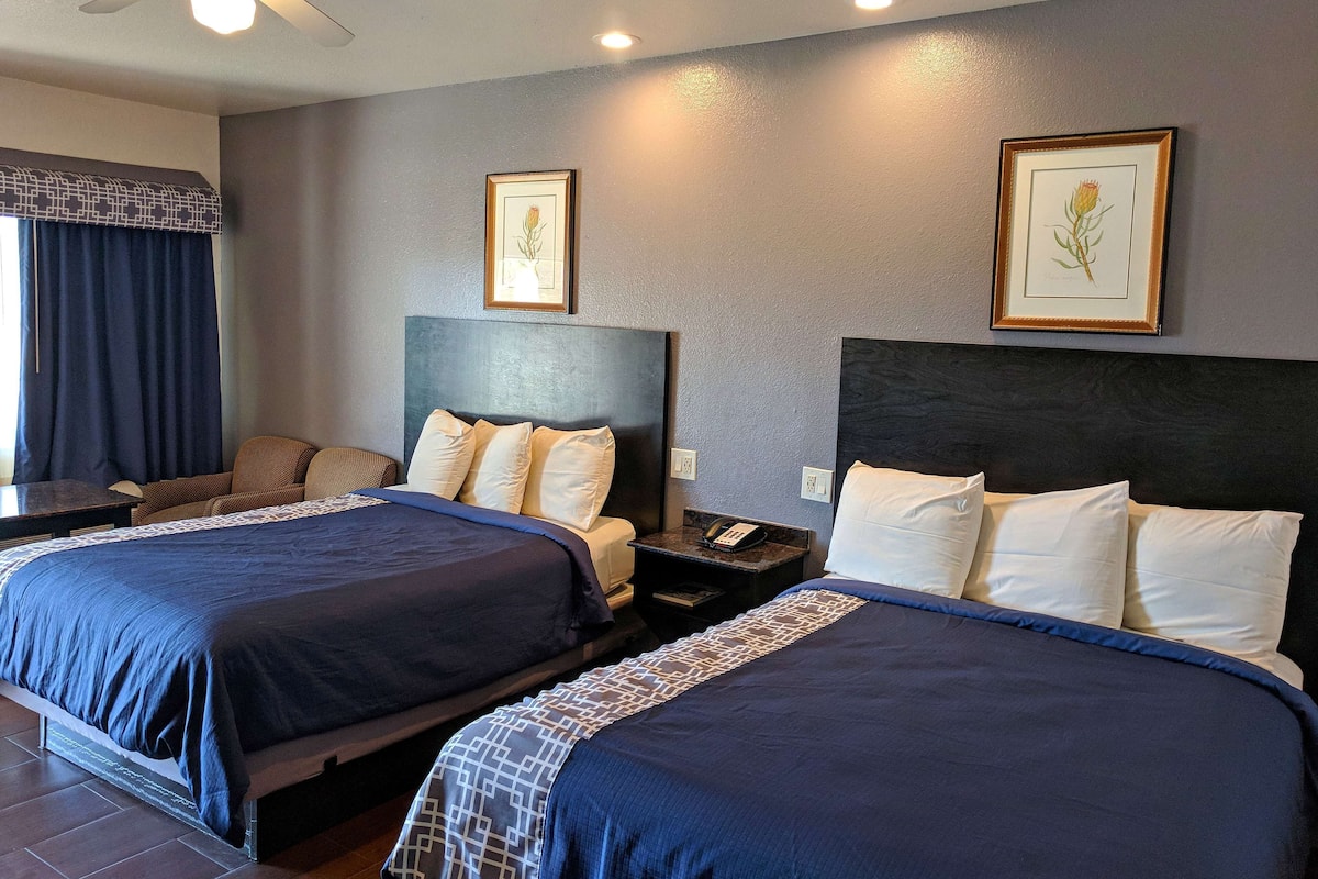Une chambre d’hôtel avec deux lits, un bureau, un téléphone et un ventilateur de plafond.