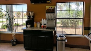 A small coffee station with a coffee machine, cups, and a trash can. - Americas Best Value Inn Brownsville (Brownsville)