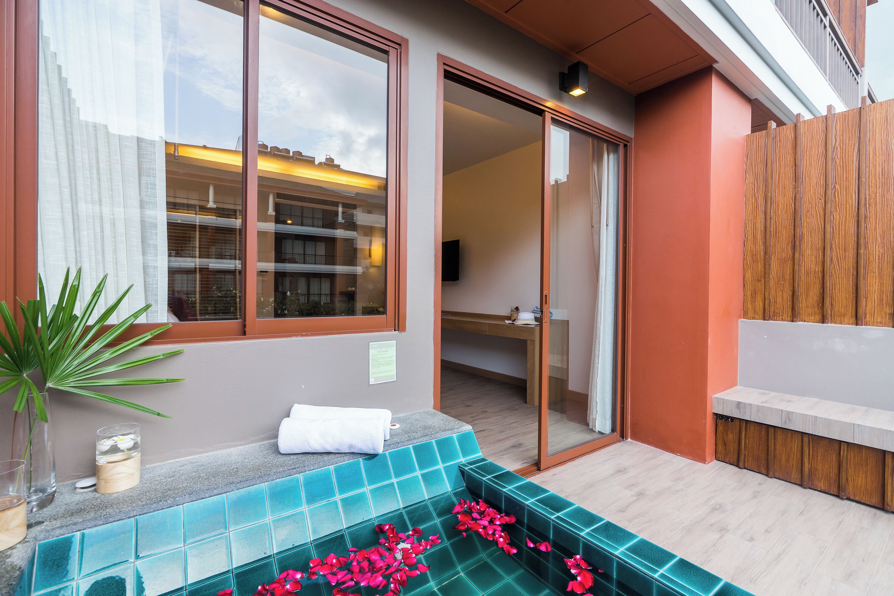 Un baño moderno con cabina de ducha de vidrio, un banco de madera y una planta en maceta.