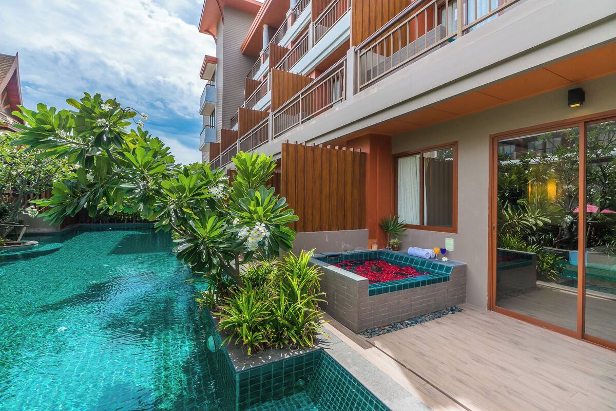 A modern hotel with a swimming pool, outdoor seating, and lush greenery.