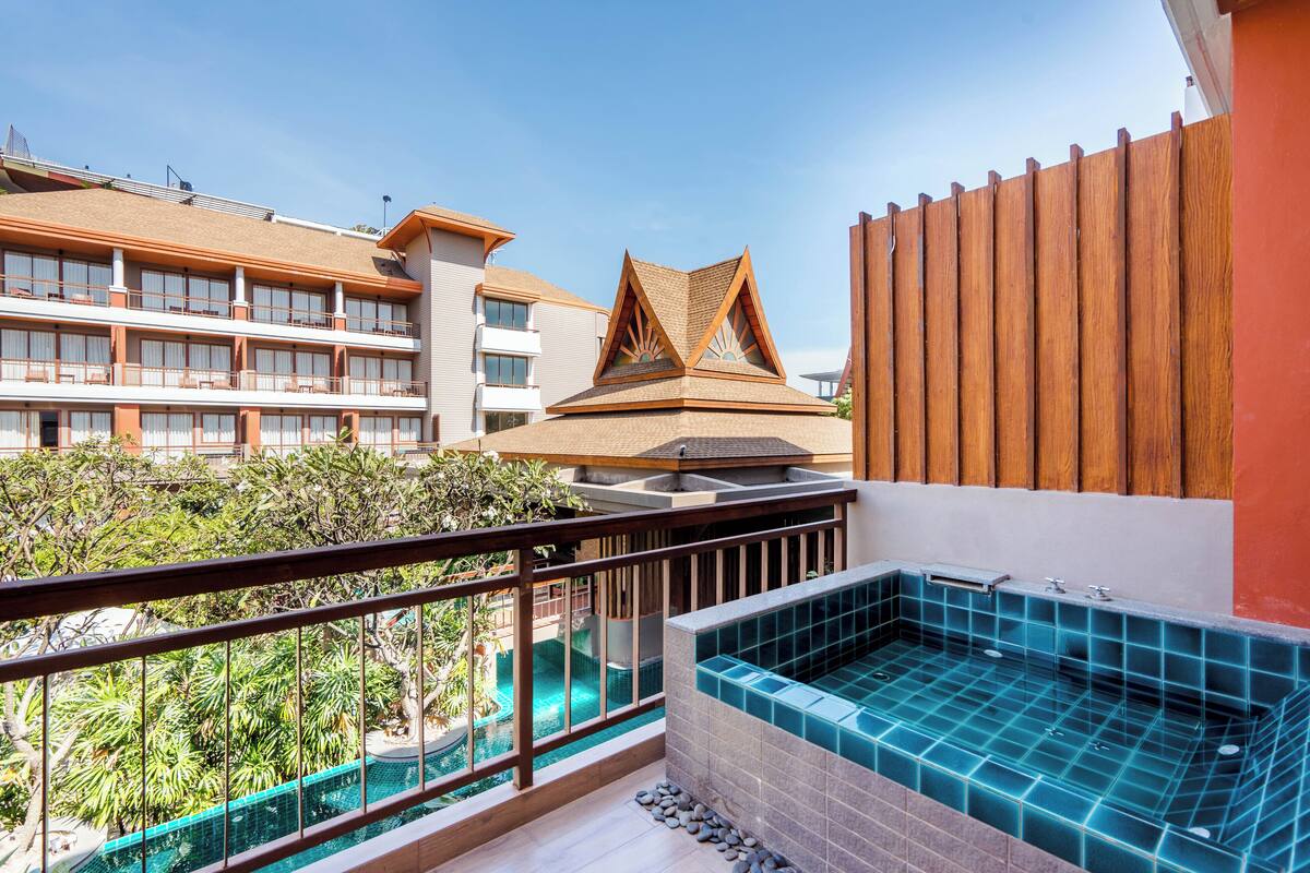 A hotel balcony with a view of a swimming pool and a spa area.
