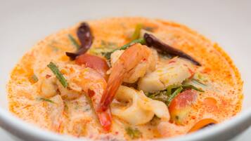 A bowl of seafood soup with shrimp, squid, and vegetables in a creamy broth.