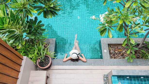 Una persona recostada en la terraza de la piscina, con vista a la alberca.