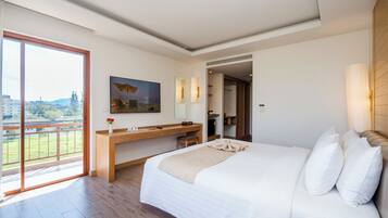 Una habitación de hotel moderna con una cama grande, un escritorio de madera, un balcón y vistas a la ciudad.