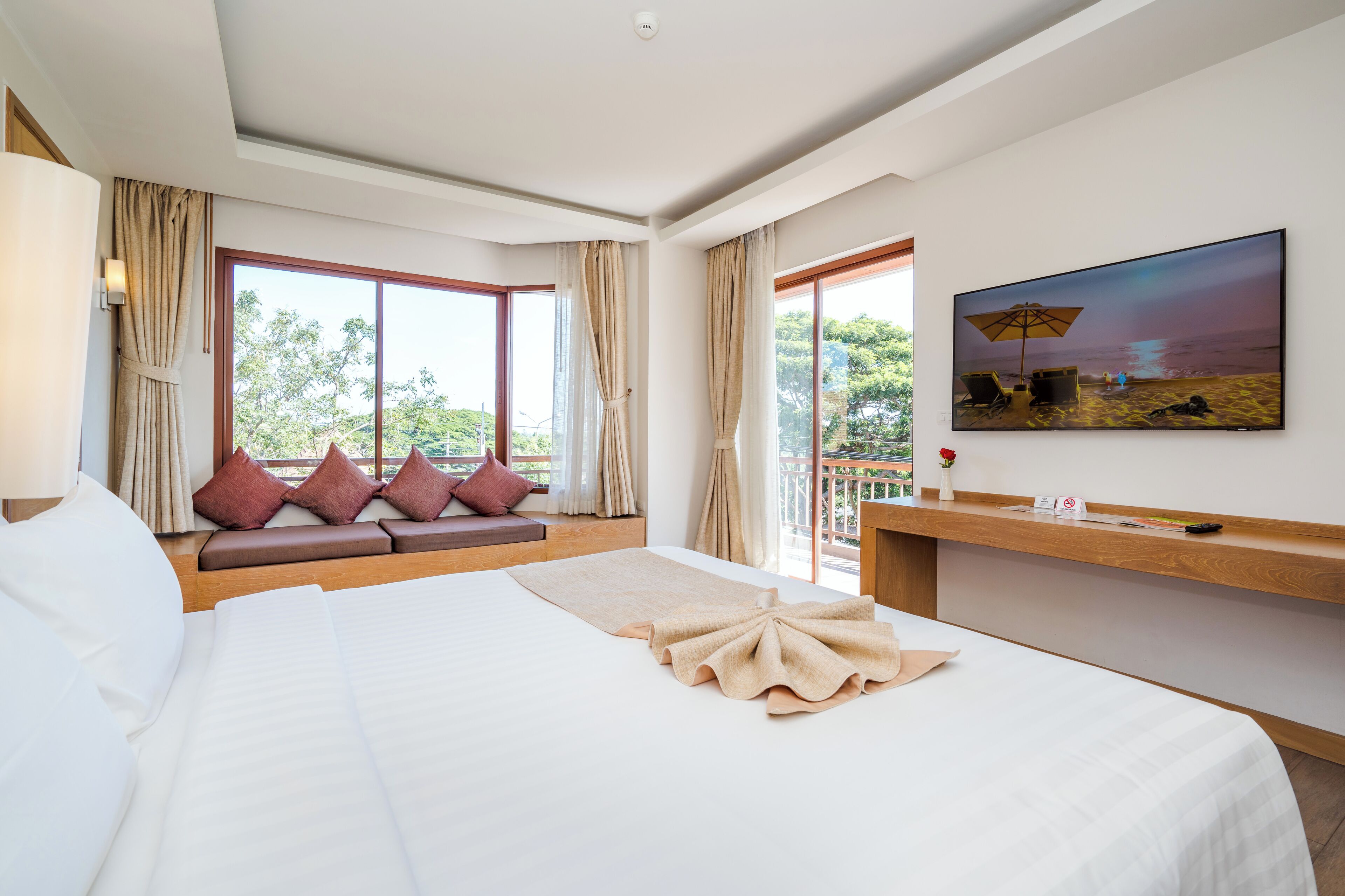 Una habitación de hotel con una cama grande, una zona de estar junto a la ventana y un cuadro en la pared.
