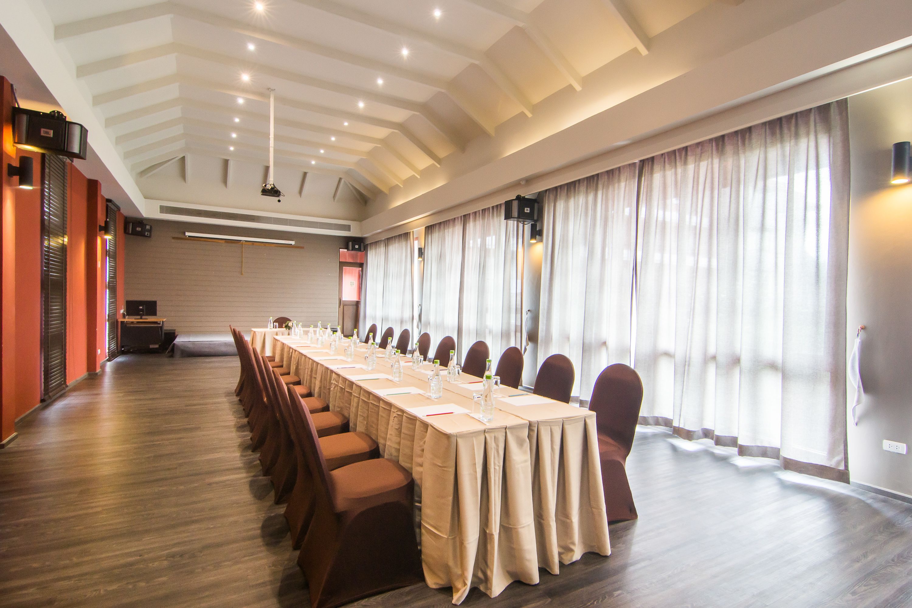Un salón de conferencias con una larga mesa, sillas y un diseño moderno en el techo.