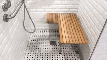 A shower area with white tiled walls, a wooden bench, and a handheld showerhead.