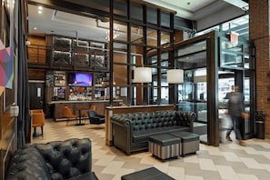 A modern lobby with a bar area, seating, and a large television screen. - Archer Hotel New York (New York)
