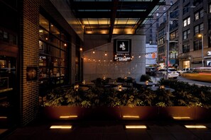 Un espacio al aire libre con mesas y sillas, un letrero que dice 'Hotel Bar Spyglass' y una calle con coches al fondo.