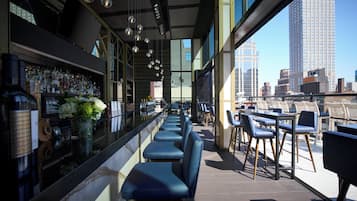 Um bar com balcão extenso, banquetes azuis e vista para a cidade.