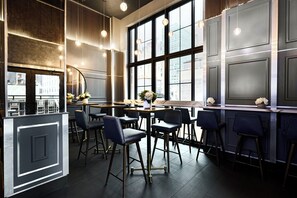 A modern bar area with high ceilings, large windows, and bar stools. - Archer Hotel New York (New York)