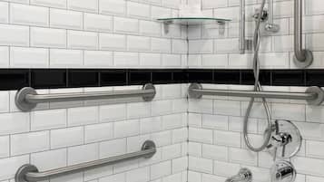 Ein modernes Badezimmer mit weißen Fliesen im U-Bahn-Stil, einer weißen Badewanne und einer Handbrause.