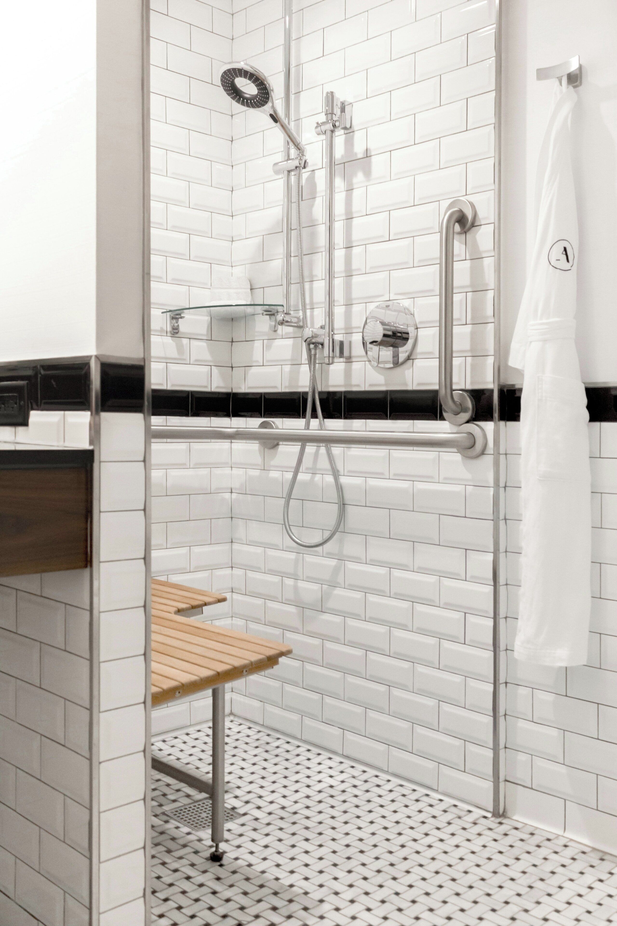 A modern shower with a glass enclosure, a handheld showerhead, a wall-mounted faucet, and a towel rack.