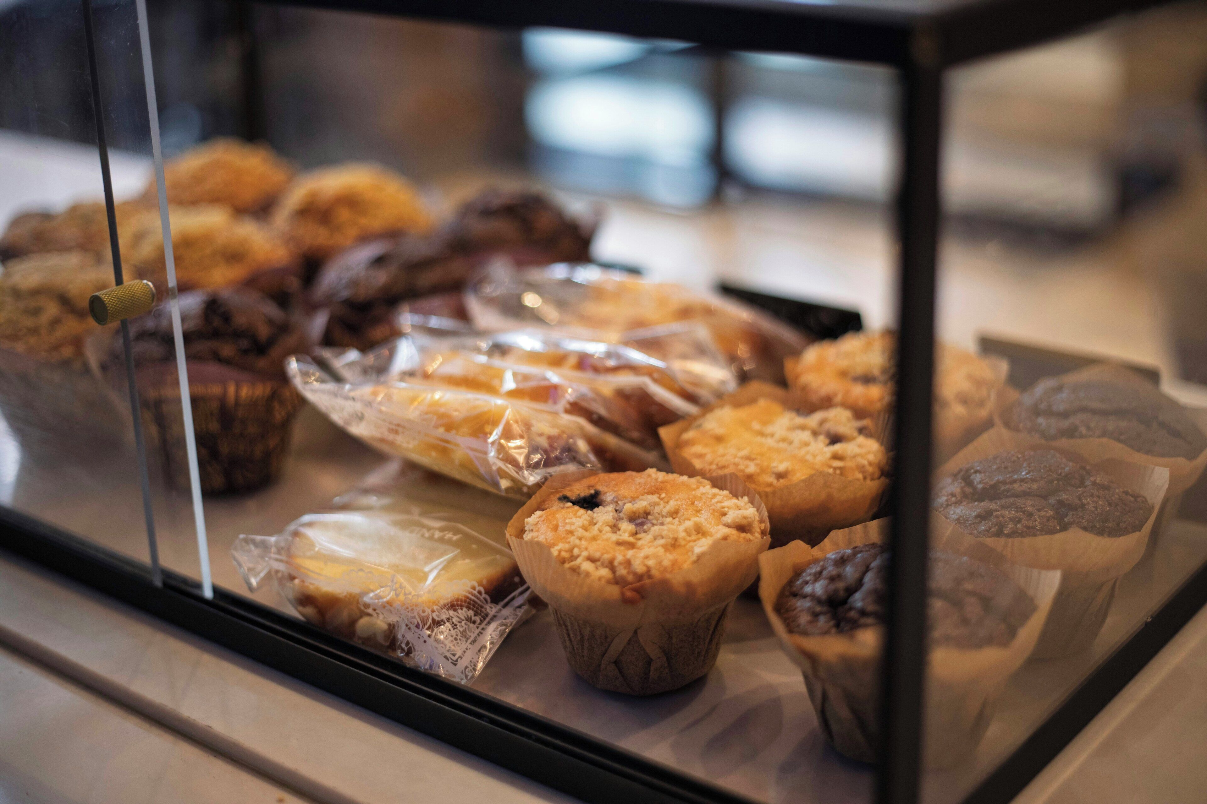 Une vitrine remplie de diverses pâtisseries, notamment des muffins et des viennoiseries, dans une boulangerie.