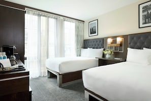 A hotel room with two beds, a desk with a coffee maker, and a window with sheer curtains. - Archer Hotel New York (New York)