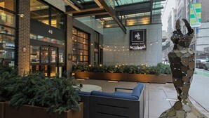 A hotel entrance with a modern design, outdoor seating, and a decorative sculpture. - Archer Hotel New York (New York)