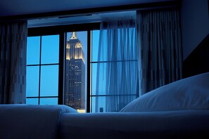 Una habitación de hotel con un ventanal grande, una cama y cortinas.