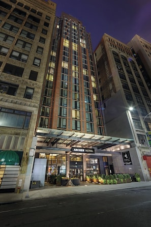 Un hotel con fachada moderna, ventanas amplias y acceso cubierto.