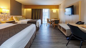 Ein Hotelzimmer mit zwei Betten, einem Schreibtisch, einem Stuhl, einem Fernseher und einem Telefon.