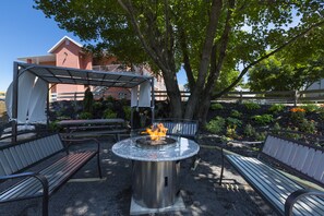 Un espace extérieur aménagé avec un foyer, des bancs et une pergola.