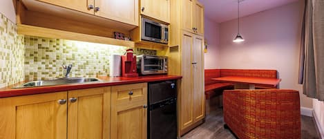 A compact kitchen with wooden cabinets, a microwave, a toaster, and a sink.