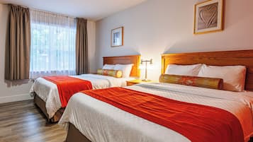 Une chambre d’hôtel avec deux lits, des têtes de lit en bois et une grande fenêtre avec des rideaux.