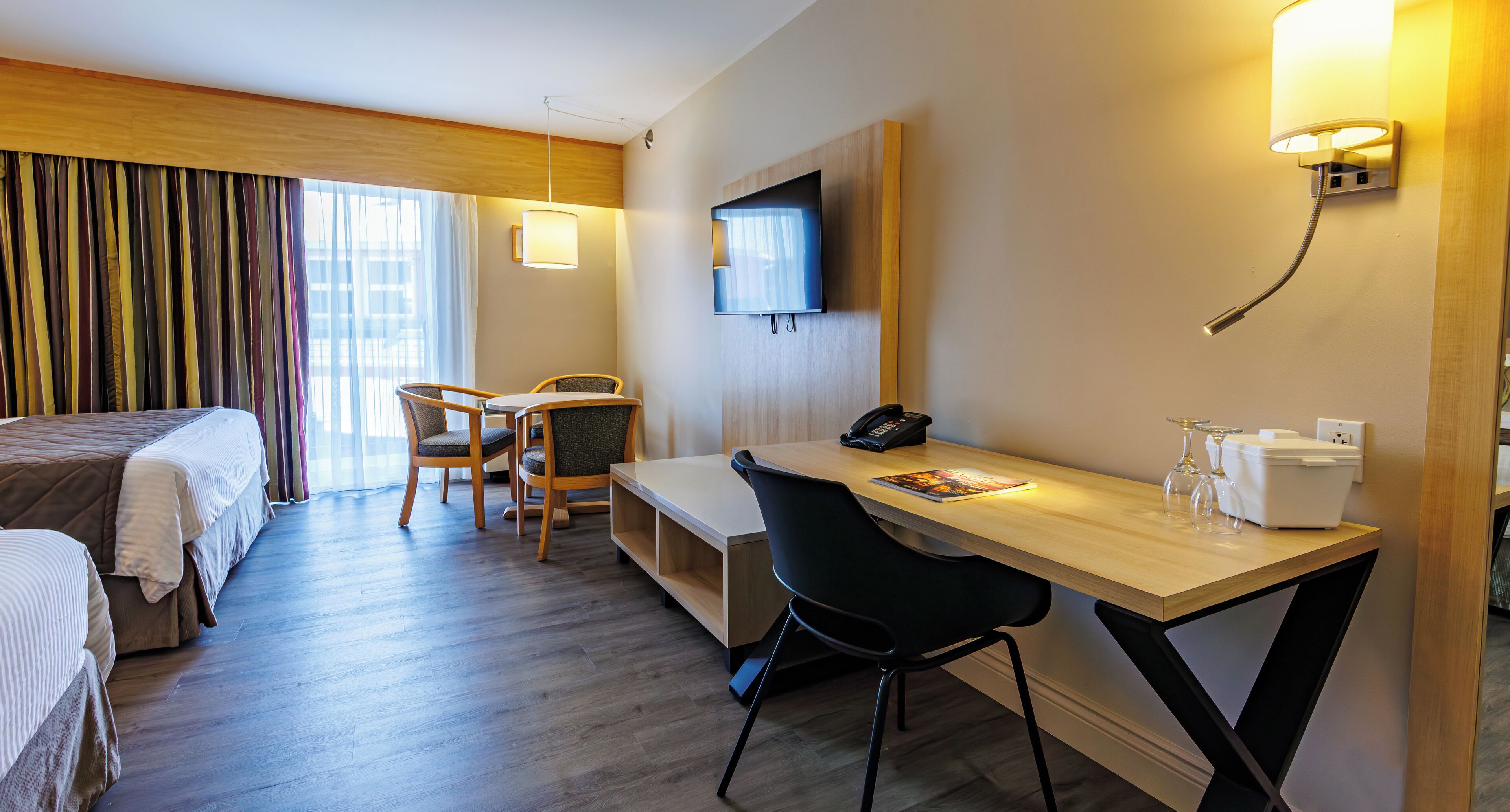 Una habitación de hotel con cama, escritorio, silla, televisor y teléfono.