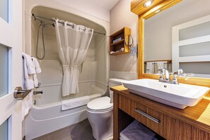 Un baño moderno con bañera, inodoro y tocador con lavabo y espejo.