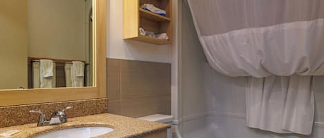 Un baño con encimera de granito, dos lavamanos, inodoro y bañera.