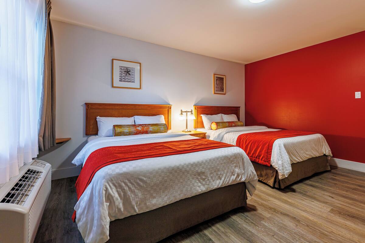 Ein Hotelzimmer mit zwei Betten, einem Heizkörper und einer roten Wand.